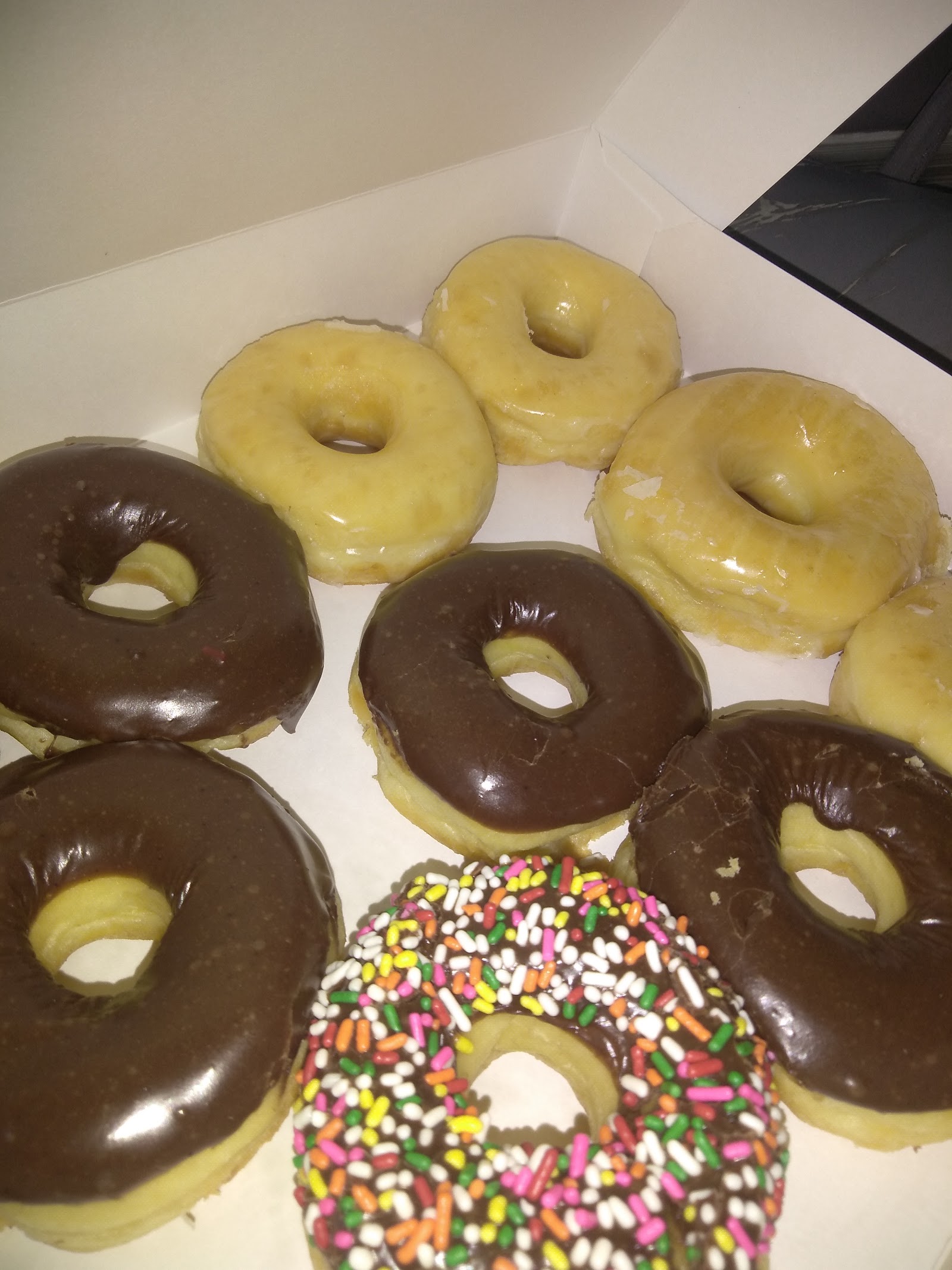 Assorted glazed, chocolate and sprinkle donuts in a box